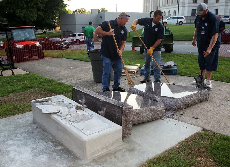 Arkansas secretary of state staff members clean up the broken pieces of the Ten Commandments monument on the state Capitol grounds June 28 after it was smashed by a car that morning, a day after it was installed. A replacement monument has been completed but not yet installed.