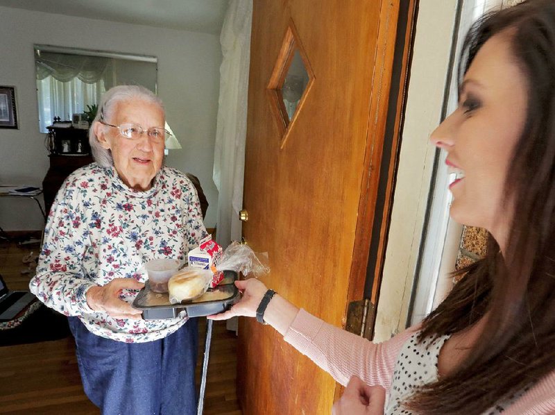 Michelle Gilbert, outreach and marketing officer for CareLink, hands a meal to Rosemary Meritt, 82, Oct. 26. Meritt has been receiving Meals on Wheels for about a year. 