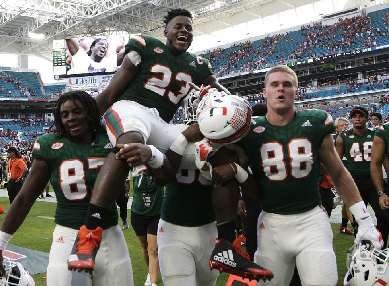 Miami tight end Christopher Herndon IV (23) is carried off the field by teammates Saturday after the No. 3 Hurricanes defeated Virginia 44-28 in Miami. The Hurricanes extended their winning streak to 15 games and secured their first season with at least 10 victories since 2003. 