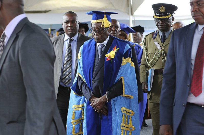 Zimbabwe's President Robert Mugabe (center) leaves after presiding over a graduation ceremony Friday at Zimbabwe Open University on the outskirts of Harare.