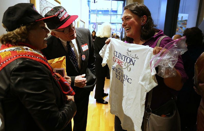 Angela Danovi (right) shows off her Clinton-Gore ’96 campaign T-shirt to Marian and David Hodges during Friday’s gathering at the Butler Center for Arkansas Studies in downtown Little Rock. 
