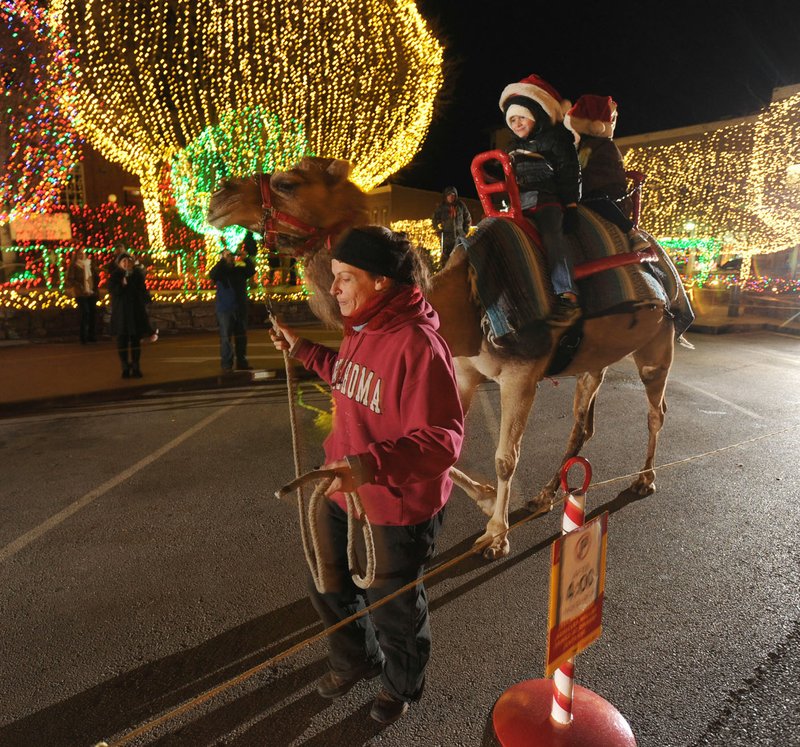 File Photo Landon Albright and Kynley Albright of Boerne, Texas, smile as they ride atop a camel named Blackjack on the Fayetteville square last year. Camels and carriages both return to Lights of the Ozarks the Friday after Thanksgiving.