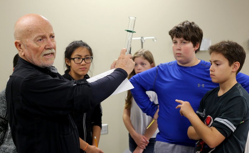 Floyd Watson, a teacher at the Tyson School of Innovation, explains Thursday the use of a graduated cylinder to seventh-graders in his science class at the Springdale school.