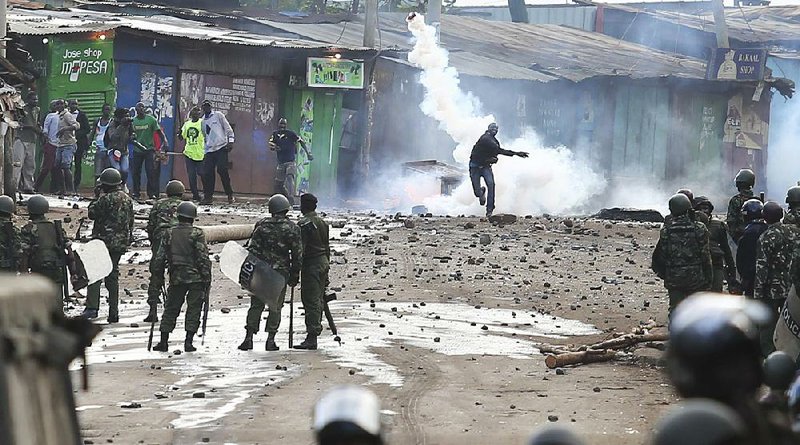 A supporter of opposition leader Raila Odinga throws a canister of tear gas toward riot police during clashes Sunday in Nairobi, Kenya.