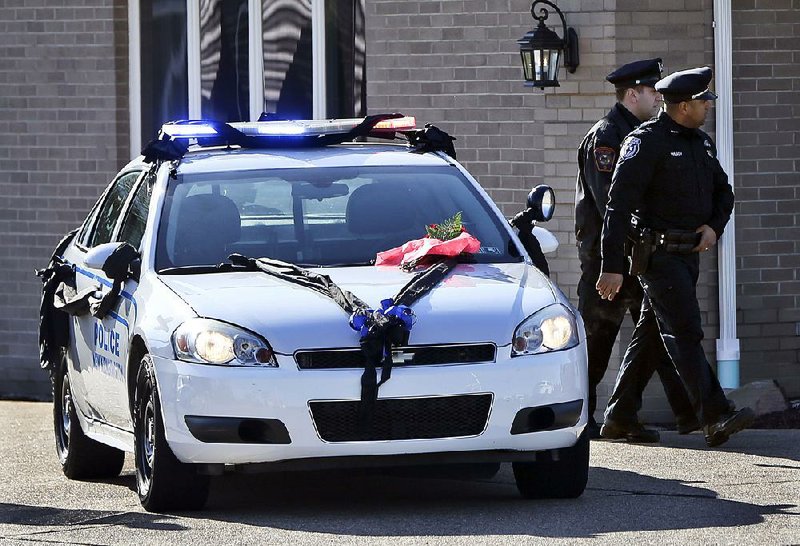 A New Kensington, Pa., police car draped in black ribbon honors slain officer Brian Shaw as a visitation is held Monday at a funeral home in Lower Burrell.