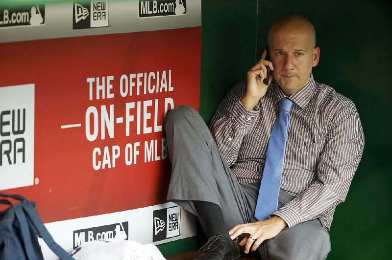 This Sept. 4, 2015, file photo shows  former Braves general manager John Coppolella talking on the phone in the dugout during batting practice before a baseball game against the Washington Nationals at Nationals Park, in Washington. Baseball Commissioner Rob Manfred placed former Braves general manager Coppolella on the permanently ineligible list. 