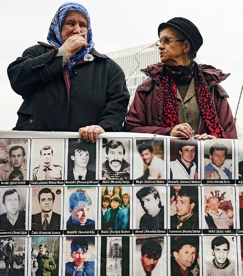 Women display images of war-crimes victims Wednesday outside the International Criminal Tribunal in The Hague, Netherlands, as they wait for the verdict on former Serb warlord Ratko Mladic. 