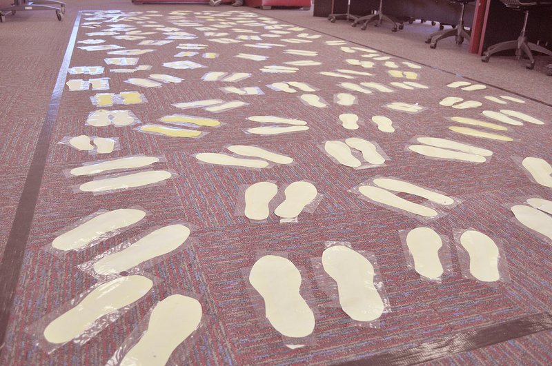 RACHEL DICKERSON/MCDONALD COUNTY PRESS At the MCHS library's World War II museum, a taped-off area of carpet represents a WWII rail car, which Jews would have been crammed into and transported to concentration camps. One hundred students' footprints are shown.