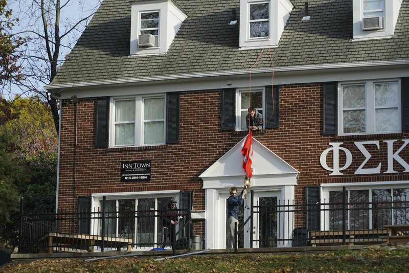 AP/DAKE KANG Phi Sigma Kappa Epsilon fraternity house members take down a flag at Ohio State University in Columbus, Ohio. Ohio State has joined a growing list of schools hitting pause on Greek life as they grapple with how to prevent hazing, alcohol misuse and other misconduct.