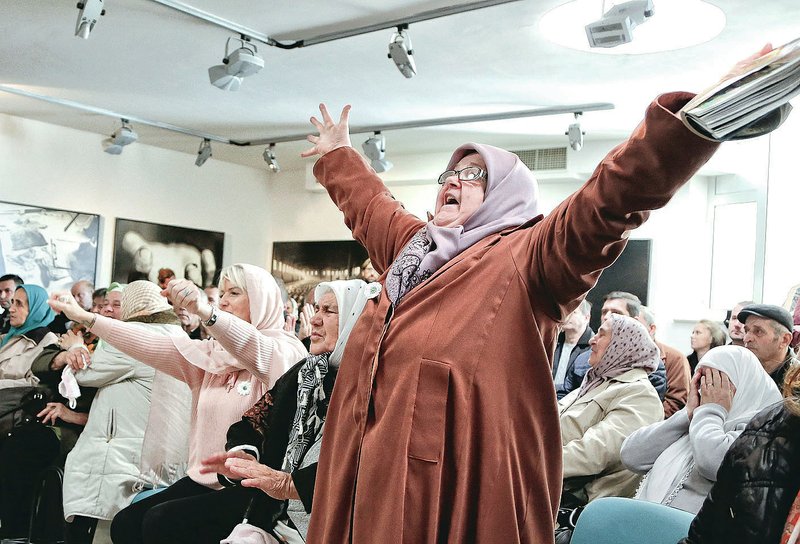 Ediba Salihovic stands up and raises her hands Wednesday as she reacts along with other Bosnian women upon hearing the sentence at the end of former Bosnian Serb military chief Gen. Ratko Mladic’s trial at the memorial center in Potocari, near Srebrenica, Bosnia. A U.N. court convicted Mladic of genocide and crimes against humanity and sentenced him to life in prison.