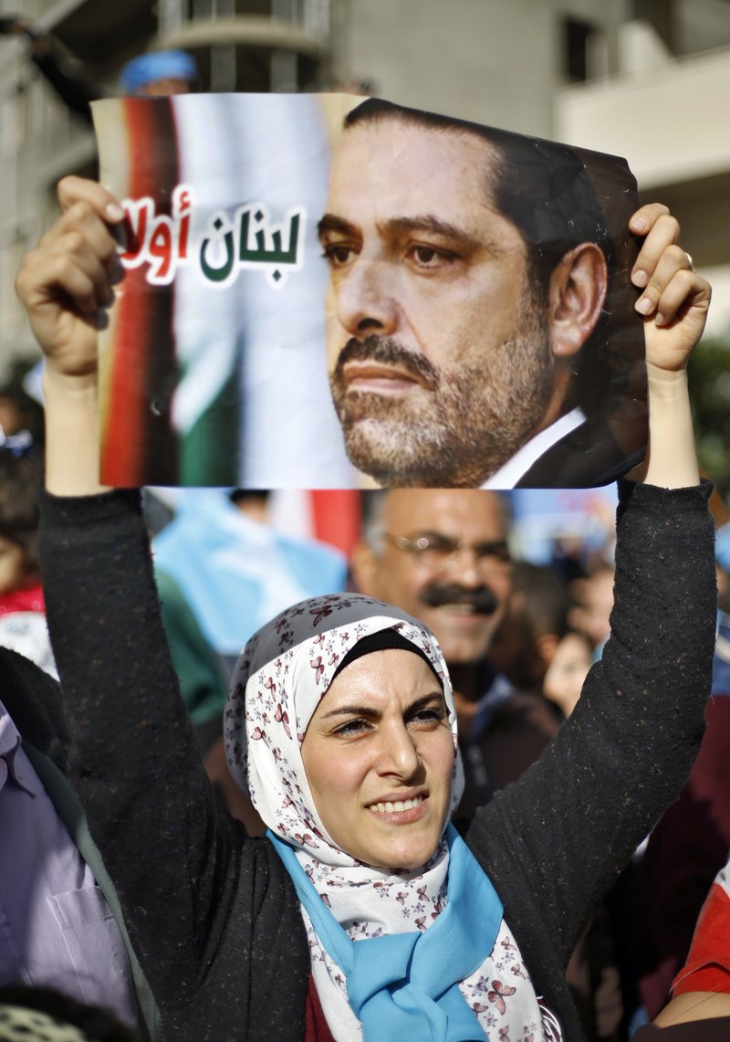 A woman holds up a picture of Lebanese Prime Minister Saad Hariri outside his residence in Beirut, Lebanon, Wednesday, Nov. 22, 2017. Hariri returned to Lebanon a day earlier and in a surprise decision, said he was putting his resignation on hold responding to a request from the president to give more time to consultations. (AP Photo/Bilal Hussein)