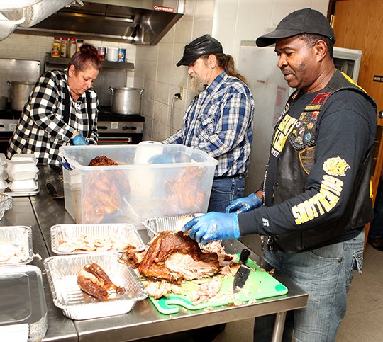 The Sentinel-Record/Richard Rasmussen TURKEY CARVING: Volunteers Melissa Allen, left, Jerry Allen and Emanuel Jernigal assist in preparing the Salvation Army's Annual Community Thanksgiving Dinner on Wednesday. The Salvation Army purchased 25 turkeys and projects they will feed approximately 250 for Thanksgiving.