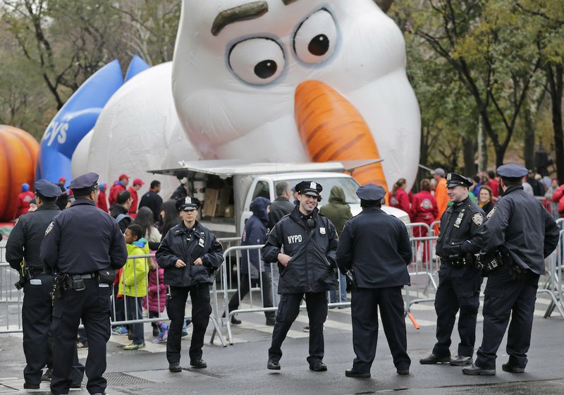 Police officers stand near the site where a large balloon of the character Olaf from "Frozen" is being inflated for the Thanksgiving Day parade in New York, Wednesday, Nov. 22, 2017. Sand-filled sanitation trucks and police sharpshooters will mix with glittering floats and giant balloons at a Macy's Thanksgiving Day Parade that comes in a year of terrible mass shootings and a deadly truck attack in lower Manhattan. 