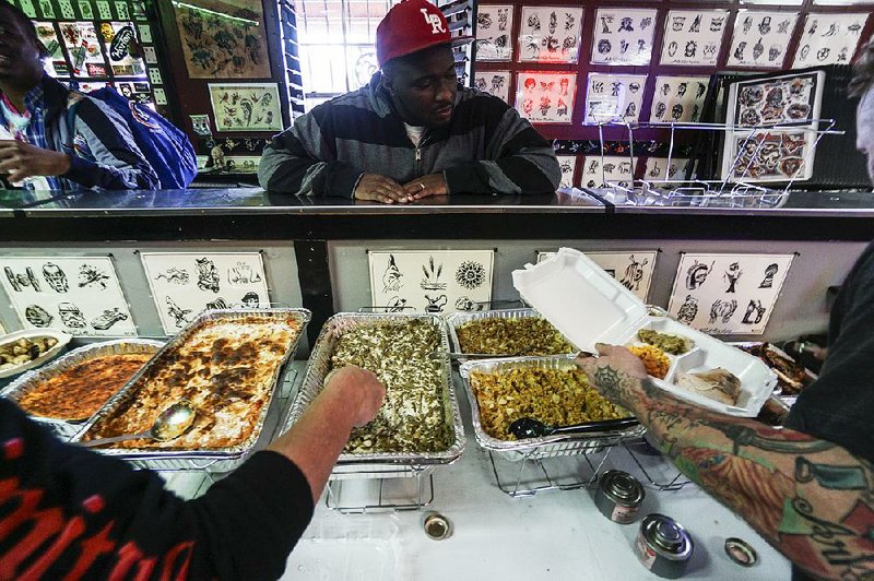 Marquise Merriweather of North Little Rock chooses his side dishes during a free Thanksgiving meal at The Parlor Tattoo in North Little Rock on Thursday. 