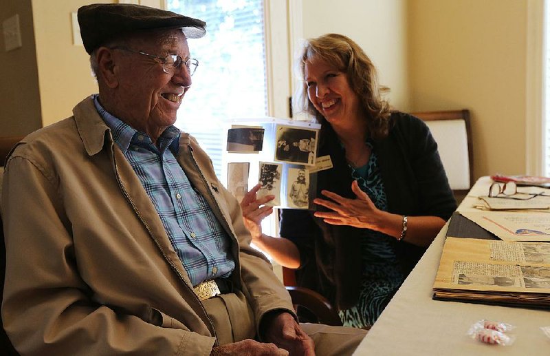 Carl Koone laughs with Anita Deason, military and veterans affairs liaison for U.S. Sen. John Boozman of Arkansas, as they look through some of Koone’s photos from his time in the Army during World War II. 