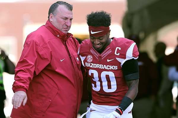 Arkansas coach Bret Bielema, left, watches as defensive back Kevin Richardson takes the field during Senior Day ceremonies prior to a game against Missouri on Friday, Nov. 24, 2017, in Fayetteville. 