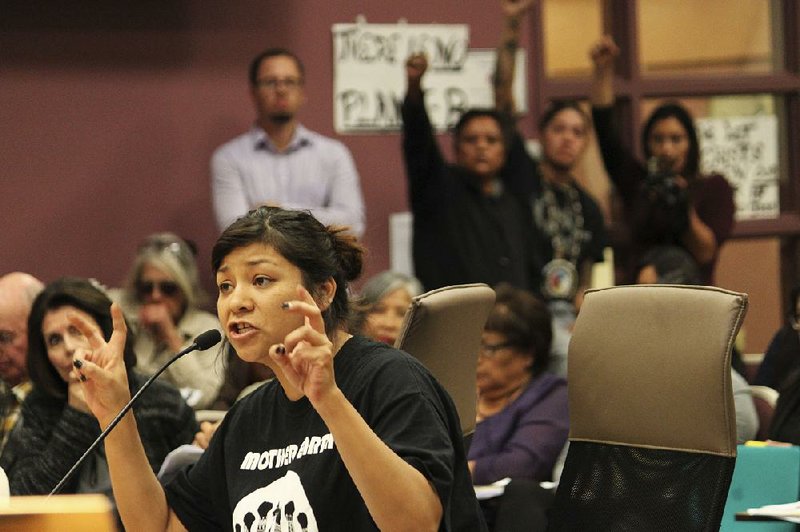 Ahjani Yepa, a Jemez Pueblo member, testifi es in opposition to a proposed ordinance that would govern oil and gas development in Sandoval County as others raise their fists in solidarity during a County Commission meeting in Bernalillo, N.M., earlier this month.