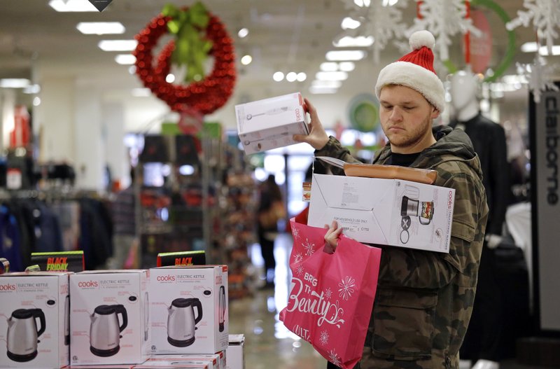 The Associated Press HOLIDAY SHOPPING: Joey Ellis adds to his armful of items while shopping for deals at a J.C. Penney store on Friday in Seattle. Black Friday has morphed from a single day when people got up early to score doorbusters into a whole season of deals, so shoppers may feel less need to be out.