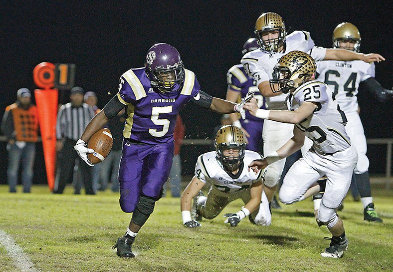 Terrance Armstard/News-Times Junction City's Hishmma Taylor tries to break free from the grasp of Clinton's Charleston Sowell during their clash in the 3A quarterfinals at David Carpenter Stadium on Friday night. The Dragons came away with a 50-43 victory, and will host Osceola next week with a berth in the state finals at stake.