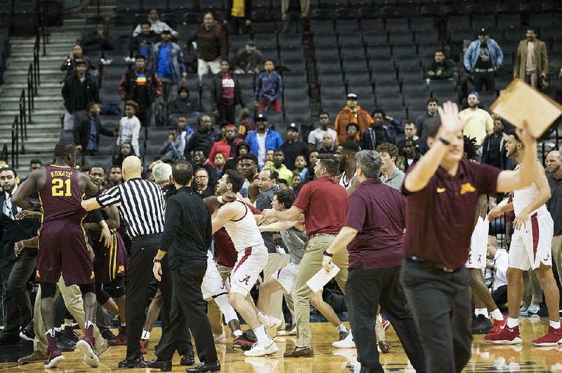 A member of the Minnesota coaching staff (right) gestures for his players to stay on the bench after a fight during the second half between Minnesota and Alabama on Saturday in New York. Minnesota won 89-84.