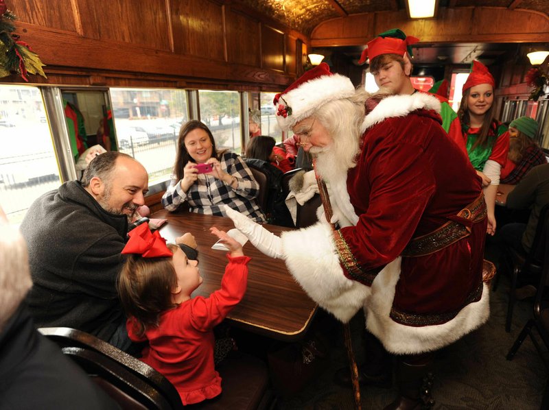 File Photo /ANDY SHUPE Olivia Scott of Springdale gets a high five from Santa Claus during last year's Children's Christmas Train at the Arkansas & Missouri Railroad depot in Springdale. The event serves as a fundraiser for the Children's Safety Center and features activities at the depot as well as a 30-minute train ride with Santa Claus and his elves to Johnson and back.