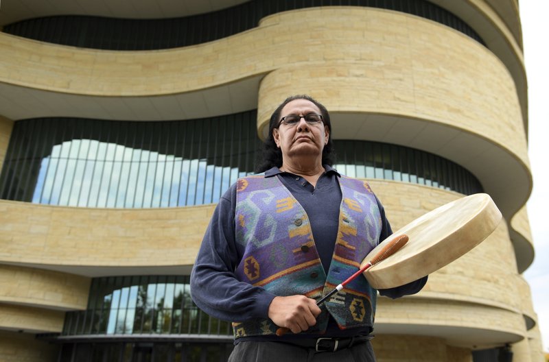 Dennis Zotigh poses for a photo outside the National Museum of the American Indian in Washington, Friday, Nov. 3, 2017. Many tribes even have their own national anthems known as flag songs that focus on veterans. They're popular among Plains tribes from which the modern powwow originated, said Zotigh of the Smithsonian National Museum of the American Indian. Powwows are social gatherings, generally with competitive dancing. (AP Photo/Susan Walsh)