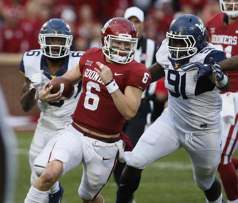 Oklahoma quarterback Baker Mayfield (6) carries past West Virginia safety Dravon Askew-Henry (6) and defensive lineman Ezekiel Rose (91) in the second quarter of an NCAA college football game in Norman, Okla., Saturday, Nov. 25, 2017. 