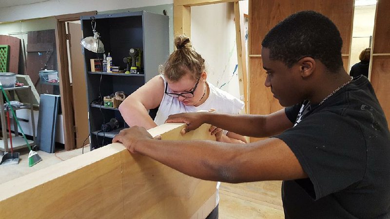 Lizzy Walkup (left) and Quincy Thurston, students at the University of Arkansas-Pulaski Technical College, work on the set of A Christmas Carol at Argenta Community Theater.