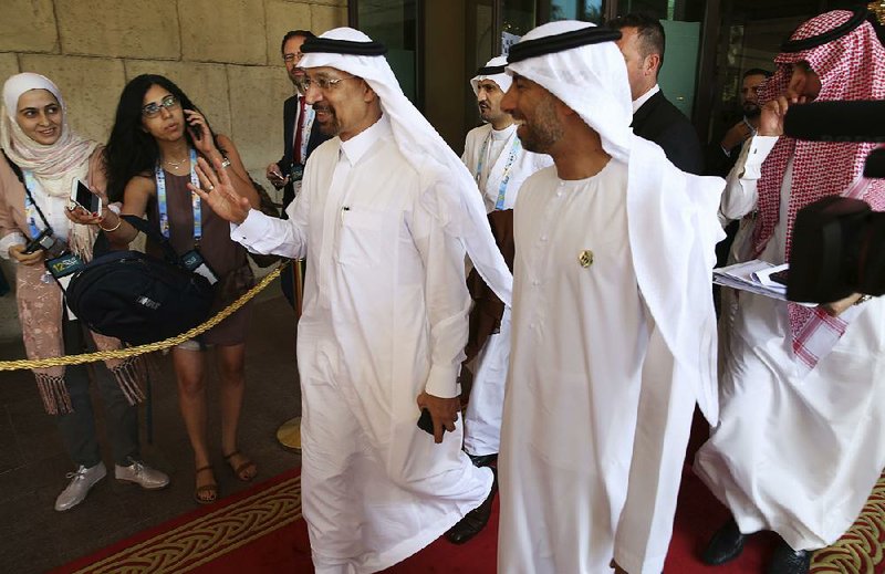 Saudi Energy Minister Khalid al-Falih (left) waves off journalists’ questions as he leaves a petrochemical conference Thursday in Dubai, United Arab Emirates. 