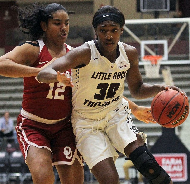 UALR’s Raeyana DeGray (right) dribbles past Oklahoma’s Gileysa Penzo during the Trojans’ 68-56 victory Tuesday night at the Jack Stephens Center in Little Rock. DeGray led all scorers with 16 points. 