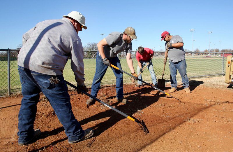 NWA Democrat-Gazette/DAVID GOTTSCHALK Chris Gibson (from left), Springdale athletic field supervisor, Jason Williams, Austin Bersi and Jose Elizalde, all with the Parks and Recreation Department, work Tuesday on the bull pen area of the Springdale High School Baseball Field at Randall Tyson Recreational Complex in Springdale.