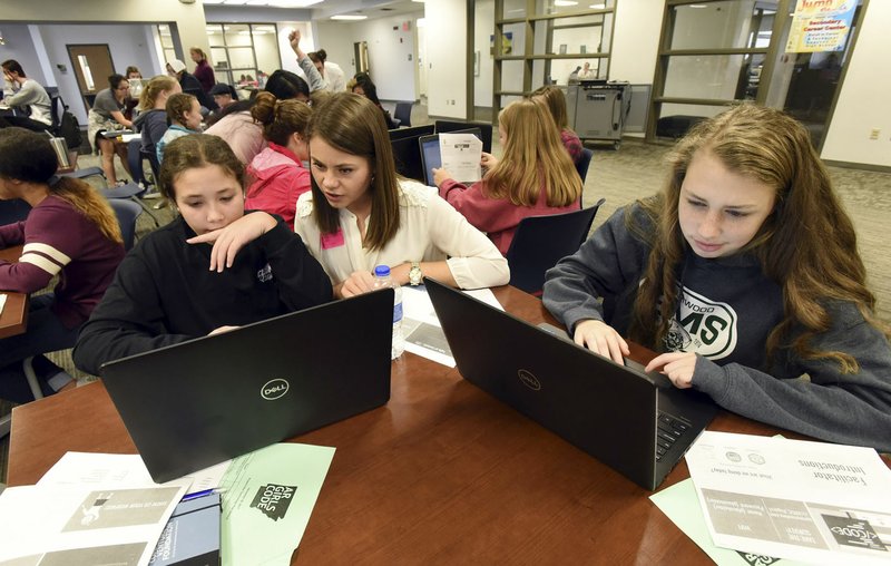 NWA Democrat-Gazette/FLIP PUTTHOFF Megan Frohardt (center), an AR Girls Can Code event organizer, helps Elmwood Middle School students Madison Rhea (left) and Vera Pelphrey (right). Middle school and high school students enhanced their computer skills during the session held at New Technology High School in Rogers.