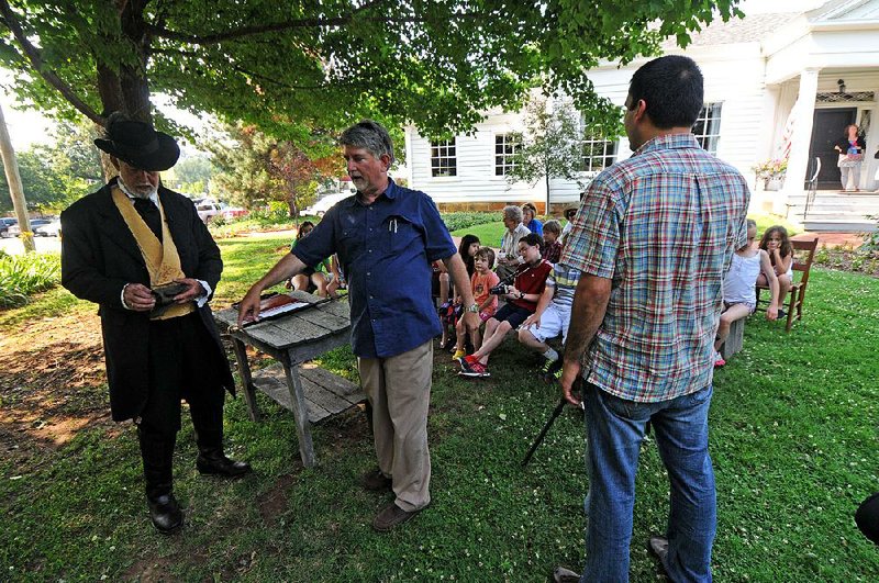 Larry Foley (center) directs Hugh Kincaid as he portrays Archibald Yell for Up Among the Hills: The Story of Fayetteville on the front lawn of Fayetteville’s Headquarters House in 2011. Photographer/ broadcast journalism instructor Hayot Tuchiev looks on. 