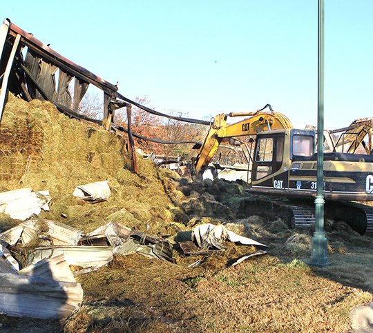 The Sentinel-Record/Richard Rasmussen CLEANING UP: A Hot Springs Street Department hydraulic excavator was used to help fully extinguish a fire that began Monday night in a Williams Brothers Feed Store barn at 439 Broadway St.