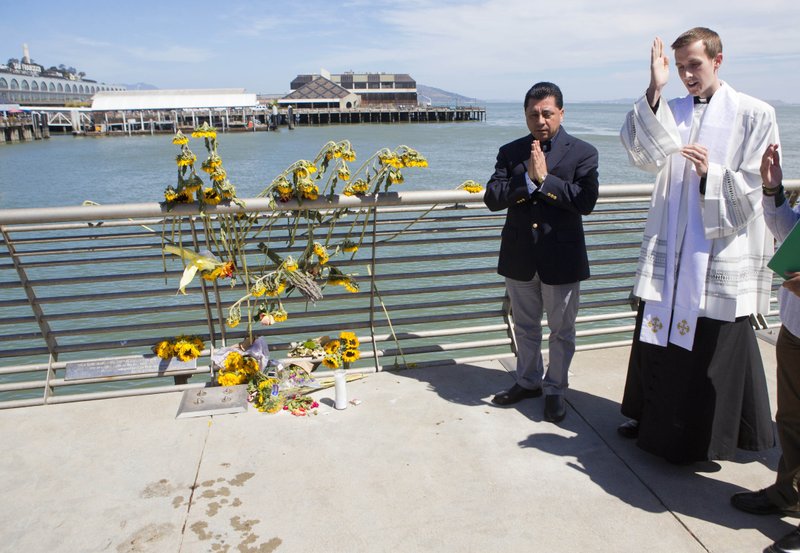 FILE - In this July 6, 2015 file photo, Father Cameron Faller, right, and Julio Escobar, of Restorative Justice Ministry, conduct a vigil for Kathryn Steinle on Pier 14 in San Francisco. A jury has reached a verdict Thursday, Nov. 30, 2017, in the trial of Mexican man at center of immigration debate in the San Francisco pier shooting. (AP Photo/Beck Diefenbach, File)