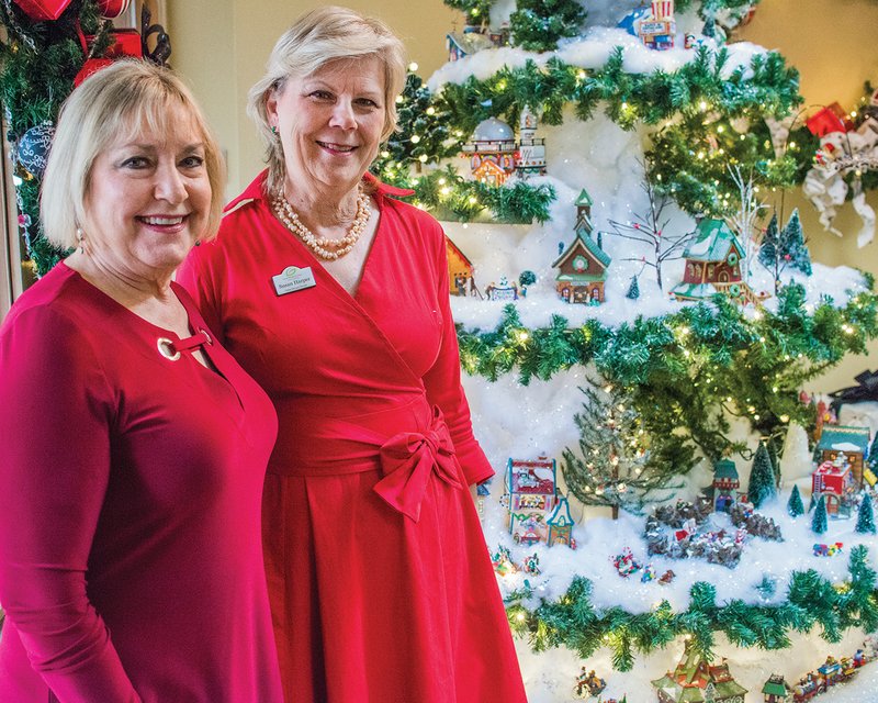 Dianne House, left, and Susan Harper, director of volunteers at Garvan Woodland Gardens, stand in front of the Christmas display featuring pieces from the Department 56 North Pole Village that House donated to the gardens in Hot Springs. The holiday display can be viewed through Dec. 31 in the Magnolia Room of the Pratt Welcome Center.