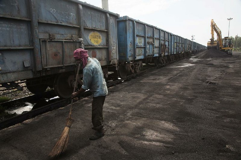 A worker sweeps up spilled petroleum coke in July at a rail yard in Rampur, India, about 130 miles from New Delhi.  
