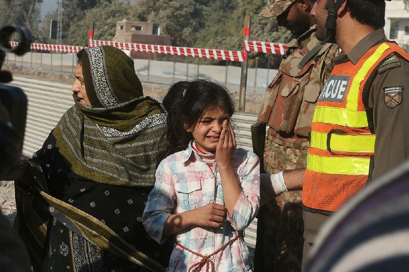 Relatives of officials trapped inside an agricultural research complex in Peshawar in northwest Pakistan wait at a police line Friday while police and soldiers battle Islamist militants attackers. 