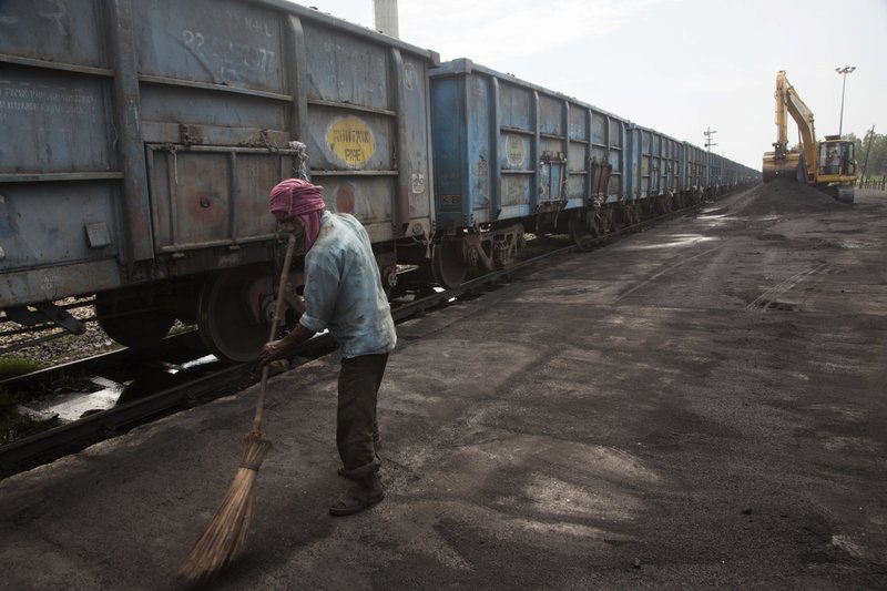 In this July 14, 2017 photo, Baburam sweeps domestically produced petroleum coke to be transported onto trucks hired by local factories in Rampur about 210 kilometers (130 miles) from New Delhi, India. The petcoke being burned in countless factories and plants is contributing to dangerously filthy air in India, which already has many of the world's most polluted cities. India''s energy-hungry industries like petcoke because it's cheaper and burns hotter than coal; they also defend their use by saying they're recycling a waste that's being produced anyway. (AP Photo/Vaishnavee Sharma)