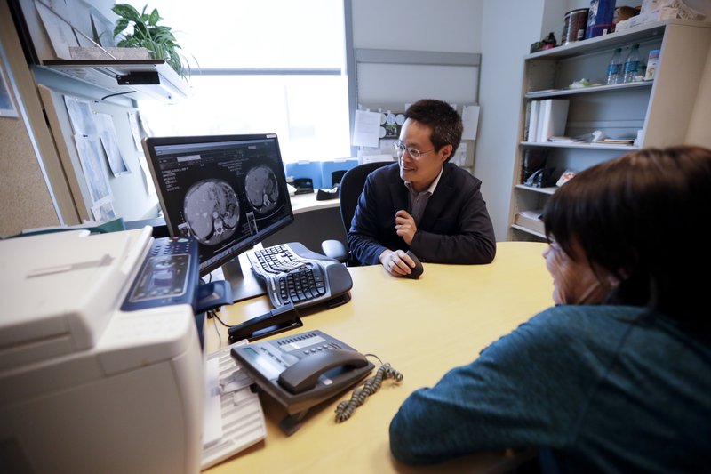 FILE - In this Aug. 15, 2017 file photo, patient Alison Cairnes, foreground, looks at images with her doctor Shumei Kato at the University of California San Diego in San Diego. Tumor profiling that sequenced Cairnes' cancer genes helped identify a treatment that proved effective for her gastric cancer. On Thursday, Nov. 30 the U.S. Food and Drug Administration approved one such test by Foundation Medicine.  (AP Photo/Gregory Bull, File)