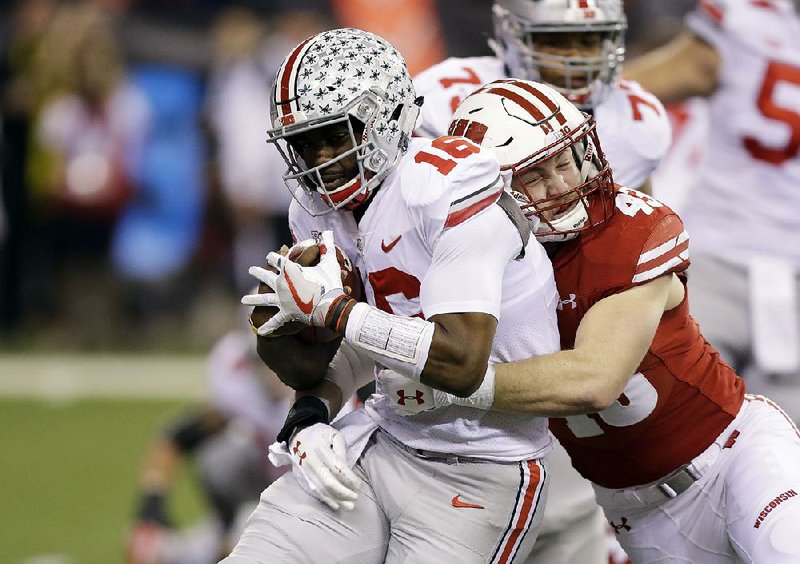 Ohio State quarterback J.T. Barrett (left) is tackled by Wisconsin’s Ryan Connelly during the Buckeyes’ 27-21 victory over Wisconsin in the Big Ten championship game Saturday night in Indianapolis. 