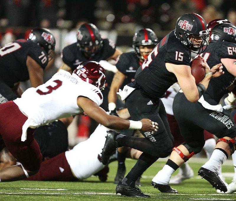 Arkansas State quarterback Justice Hansen slips past Troy safety Kris Weatherspoon on Saturday to give the Red Wolves a 10-7 lead, but ASU was outscored 25-15 in the second half in a 32-25 loss to the Trojans in Jonesboro.