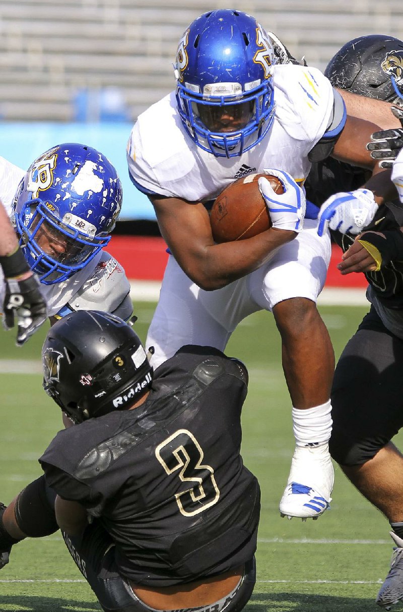 North Little Rock running back Oscar Adaway leaps over Bentonville’s Jadyn Loudermilk during Saturday’s game.