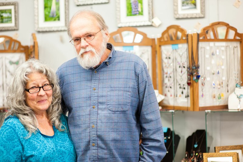 Anita and Edward Hejtmanek, founders of Heartwood Gallery, pause in front of a display of Anita’s stained glass jewelry.