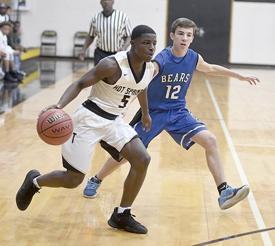 The Sentinel-Record/Mara Kuhn COURT KING: Hot Springs guard J.J. Walker (5) drives past Sylvan Hills guard Jordan Rainey (12) Friday night at Trojan Fieldhouse. The Trojans outscored the Bears 14-9 in the fourth quarter to win 50-41.
