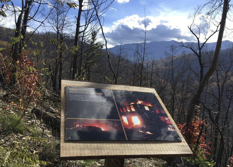 In this Nov. 21, 2017 photo, a placard on the Memorial Forest Walk at Anakeesta adventure park in Gatlinburg, Tenn. The Memorial Walk includes photos and stories of the wildfires that killed 14 people and destroyed or damaged 2,500 buildings in the Gatlinburg area last November. Work had just begun on Anakeesta when flames roared through its land. The $30 million Gatlinburg resort opened in September, with $8 million in additions planned. (AP Photo/Jonathan Mattise)