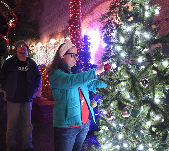 The Sentinel-Record/Mara Kuhn - Jade Snow places an ornament on the Memory Tree at Adair Park on Friday, Dec. 1, 2017. The public was invited to hang ornaments in memory of a loved one who has passed away or loved ones on active duty in the military during the holidays.