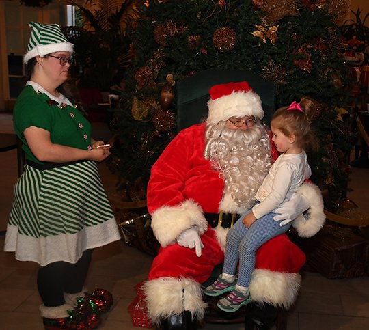 The Sentinel-Record/Mara Kuhn - Ana Blaise Rebsamen, 2, of Hot Springs visits with Santa as Elf Daphne Emery assists during the Arlington Resort Hotel & Spa's annual Gingerbread House Celebration on Friday, Dec. 1, 2017. The hotel served refreshments including hot coco, egg nog, and apple cider, along cookies and gingerbread. The Fun City Chorus also performed Christmas carols. 