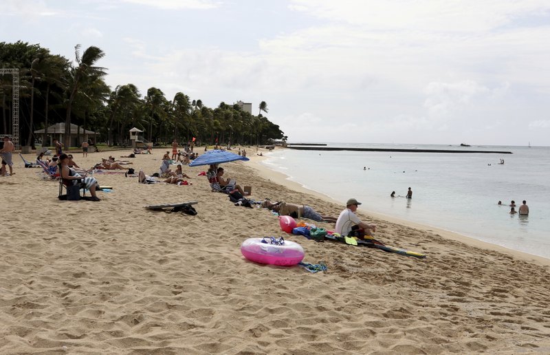 People sit on the beach and swim in the Waikiki area of Honolulu on Friday, Dec. 1, 2017. A siren blared across Hawaii on Friday for the first time since the end of the Cold War in an effort to prepare tourists and residents for a possible nuclear attack from North Korea. The state is the first to bring back the Cold War-era warning system, Hawaii emergency management officials said. The wailing siren sounded for a minute after the usual testing of the steady alert for tsunamis and other natural disasters that Hawaii residents are used to hearing. 