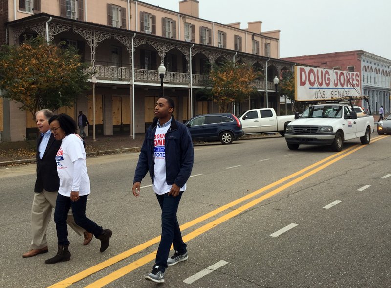 Doug Jones, left, the Democratic candidate for U.S. Senate, walks in a Christmas parade Saturday, Dec, 2, 2017, in Selma, Ala. Jones is trying to shore up support among black voters in his U.S. Senate race against Republican Roy Moore by appealing for an end to the divisiveness that has long been part of the state's politics. (AP Photo/Jeff Amy)
